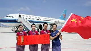 Crew members holding a Chinese national flag pose for pictures in front of a plane of the China Southern Airlines