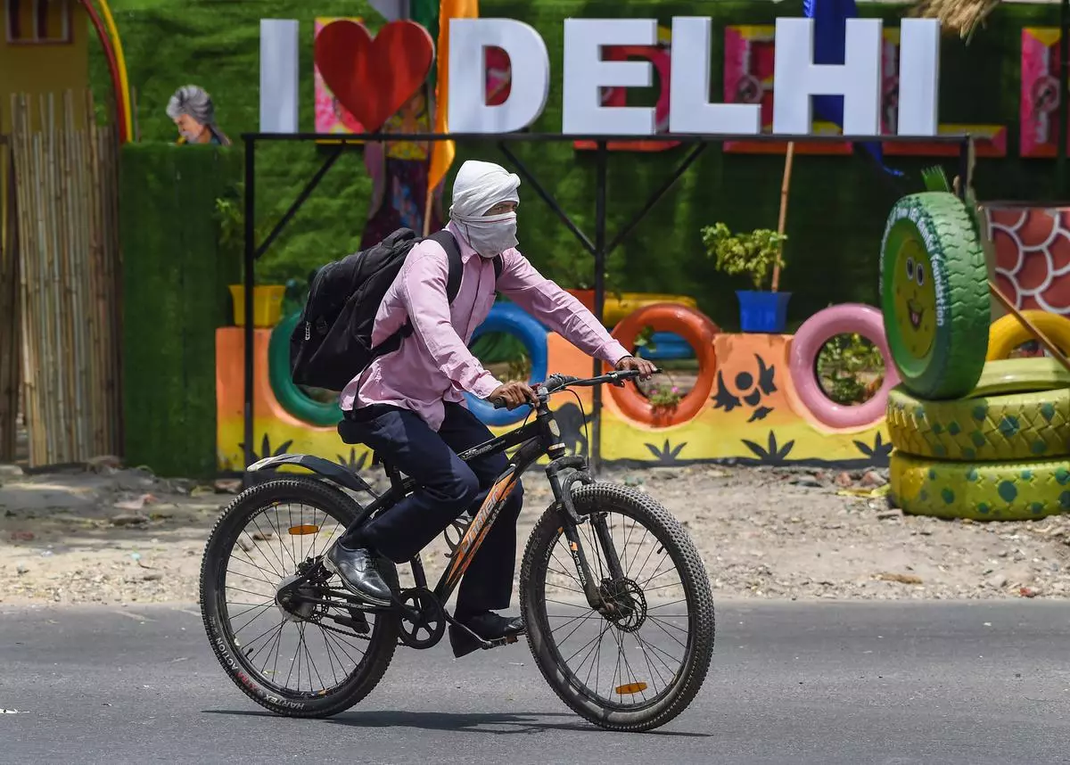A man shields his face from the heat while riding a bicycle in New Delhi. 