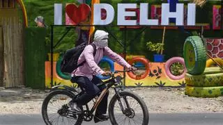 A man shields his face from the heat while riding a bicycle in New Delhi. 