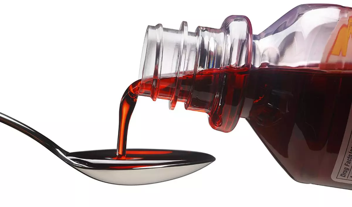 Cough syrup being poured into a spoon.