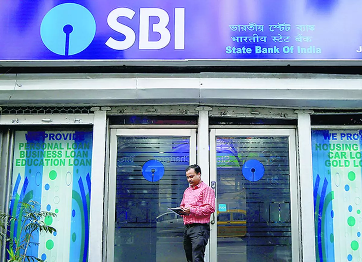 A man checks his mobile phones in front of State Bank of India (SBI) branch in Kolkata. (file photo)