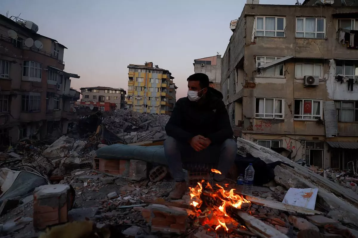 Muhammad Ibrahim sits near a campfire in the aftermath of a deadly earthquake in Hatay, Turkey February 15, 2023. 