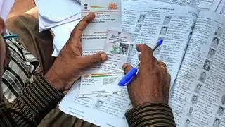A person is holding up an Aadhaar card. A person is holding up an Aadhaar card.