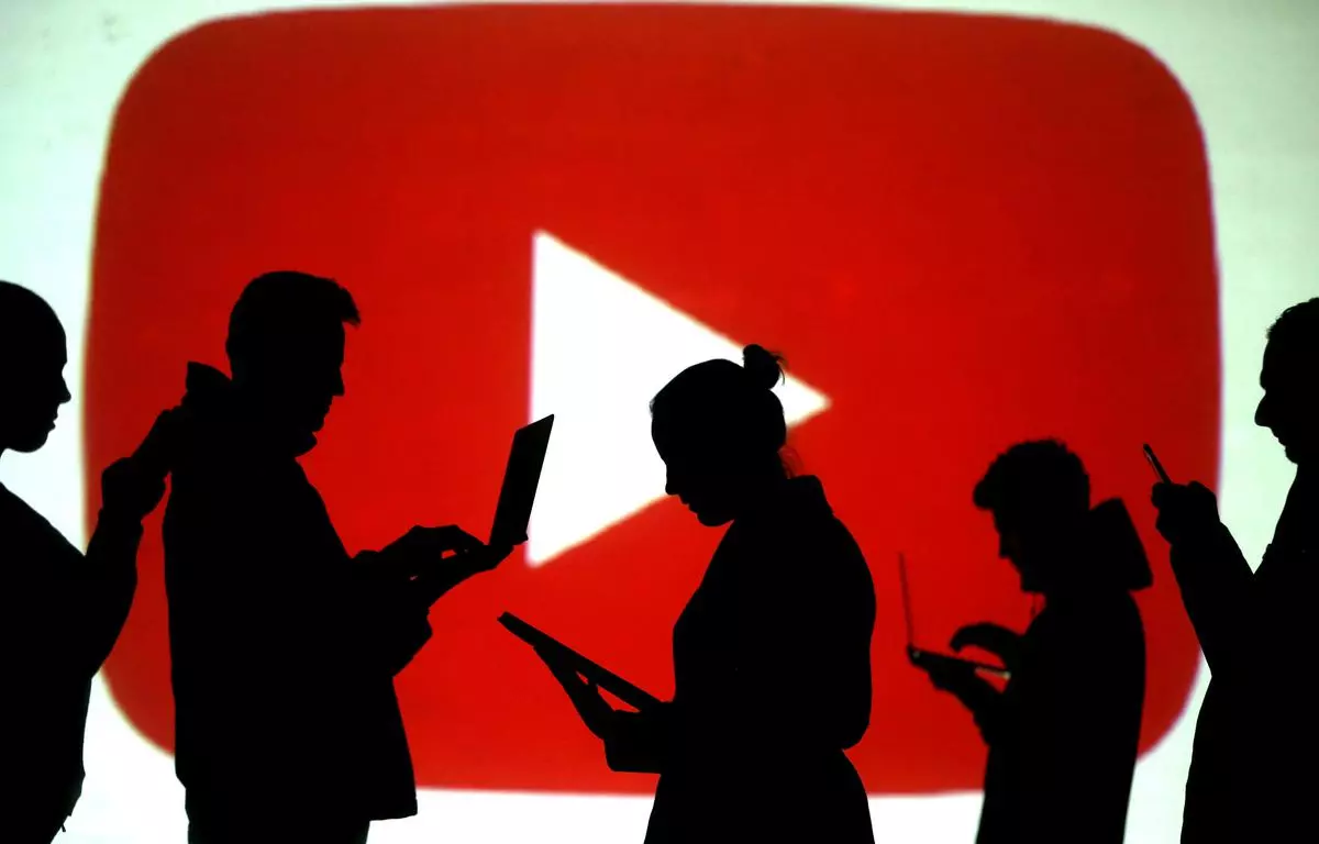 FILE PHOTO: FILE PHOTO: Silhouettes of laptop and mobile device users are seen next to a screen projection of the YouTube logo in this picture illustration. REUTERS/Dado Ruvic/Illustration/File Photo/File Photo