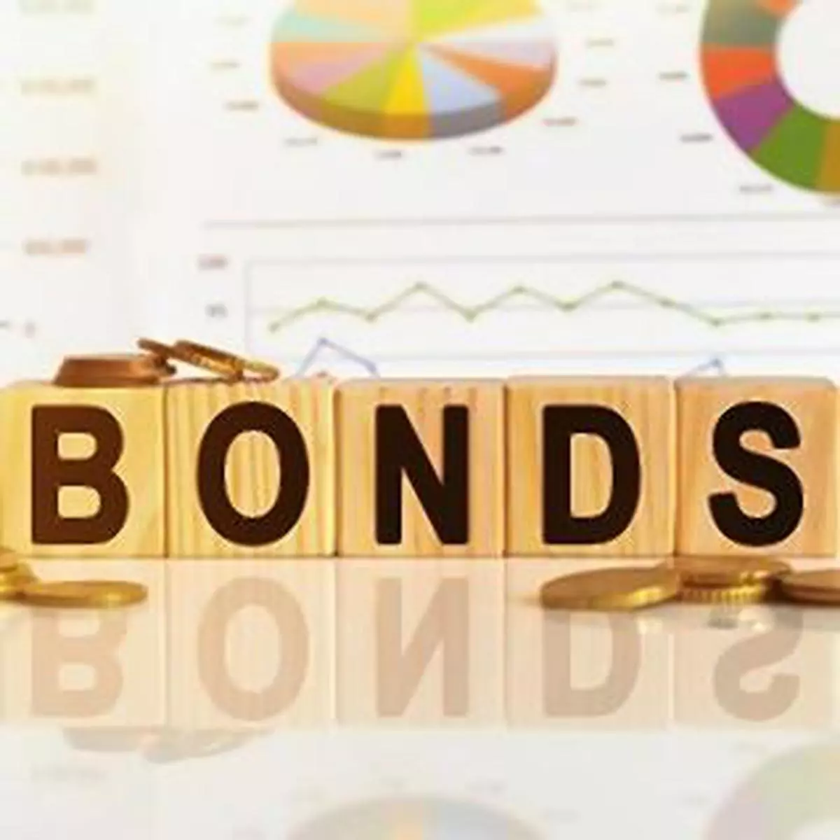 Bonds the word on wooden cubes, cubes stand on a reflective surface, in the background is a business diagram. Business and finance concept