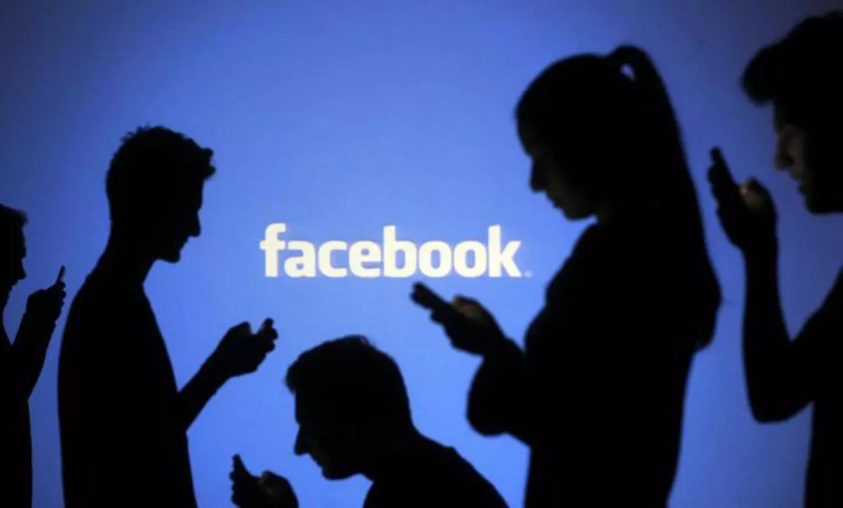 People are silhouetted as they pose with laptops in front of a screen projected with a Facebook logo, in this picture illustration taken in Zenica October 29, 2014. Facebook Inc warned on Tuesday of a dramatic increase in spending in 2015 and projected a slowdown in revenue growth this quarter, slicing a tenth off its market value. Facebook shares fell 7.7 percent in premarket trading the day after the social network announced an increase in spending in 2015 and projected a slowdown in revenue growth this quarter.   REUTERS/Dado Ruvic (BOSNIA AND HERZEGOVINA  - Tags: BUSINESS SCIENCE TECHNOLOGY BUSINESS LOGO)  