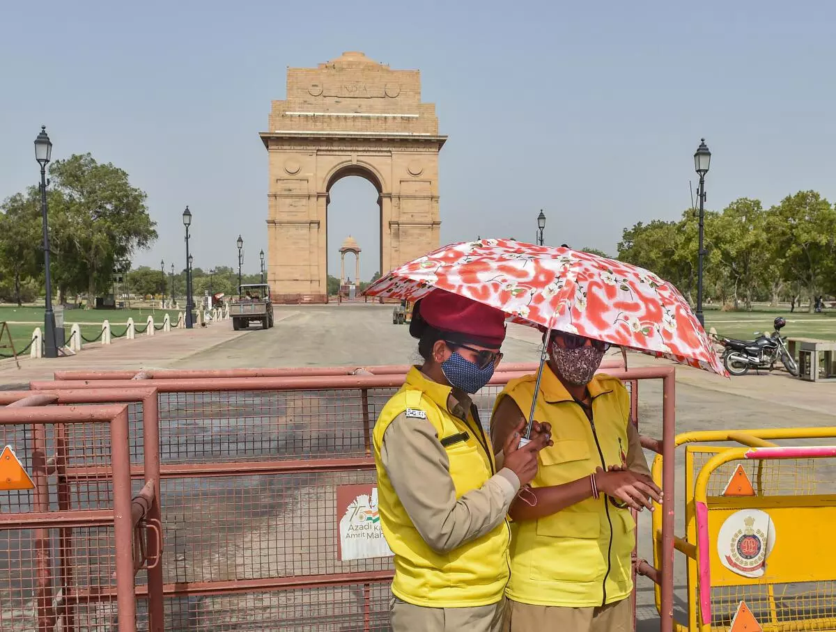 DCD volunteers use an umbrella to shield themselves from the heat on a hot summer afternoon, in New Delhi, Wednesday, June 8, 2022. (PTI)