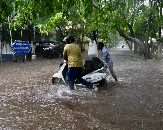 People with vehicles wade through rainwater in Chennai