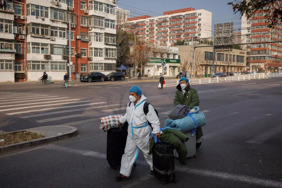 Epidemic prevention workers in protective suits carry their luggage as they walk to work as outbreaks of the coronavirus disease continue in Beijing, November 23, 2022. REUTERS