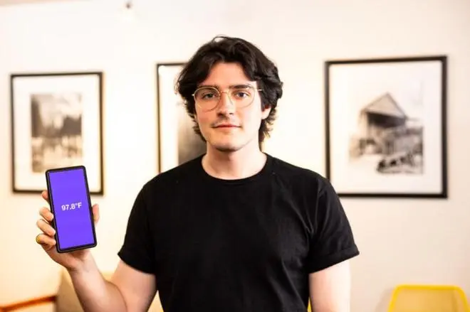 Lead author Joseph Breda holding a phone showing body temperature Lead author Joseph Breda holding a phone showing body temperature