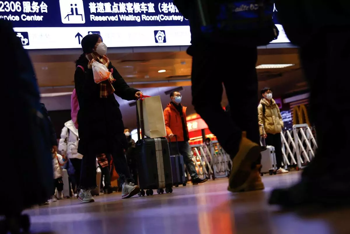 People walk with their luggage at a railway station during the annual Spring Festival travel rush ahead of the Chinese Lunar New Year, as the Covid-19 outbreak continues, in Beijing, China, January 13, 2023. REUTERS
