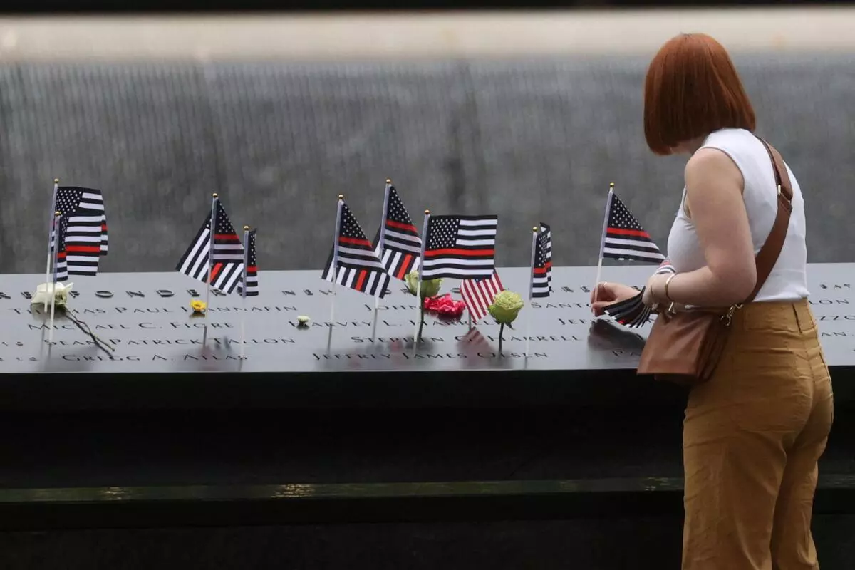 A woman places a flag during ceremonies marking the 21st anniversary of the September 11, 2001 attacks on the World Trade Center at the 9/11 Memorial and Museum in the Manhattan borough of New York City, US, September 11, 2022. REUTERS