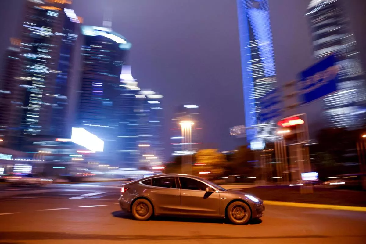 A Tesla electric vehicle (EV) drives past a crossing in Shanghai, China. REUTERS