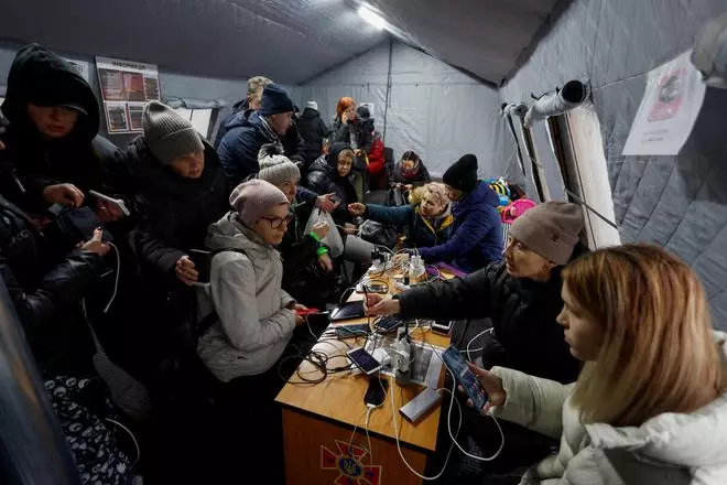 Local residents charge their devices, use internet connection and warm up inside an invincibility centre after critical civil infrastructure was hit by Russian missile attacks in Kyiv, Ukraine November 24, 2022. REUTERS