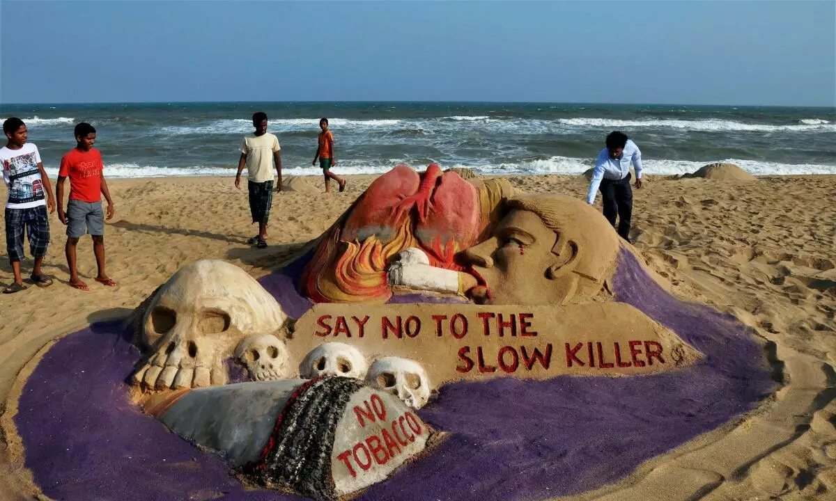 Visitors take a look at the sand sculpture made on the theme of World No Tobacco Day by sand artist Manas Sahoo at Puri beach. (PTI/File photo)