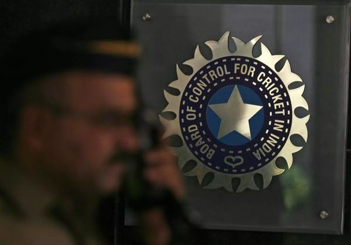 A policeman walks past a logo of the Board of Control for Cricket in India (BCCI).