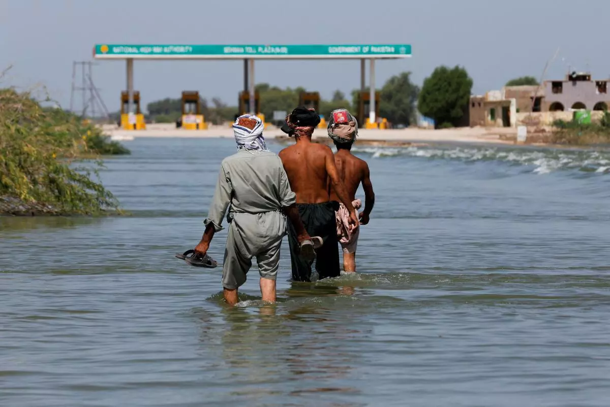 Displaced people walk on flooded highway, following rains and floods during the monsoon season in Sehwan, Pakistan, September 16, 2022. REUTERS