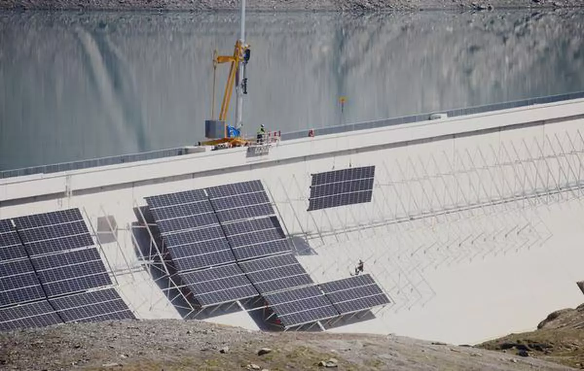 Workers place solar panels at the construction site of a large-scale photovoltaic system of Swiss energy provider Axpo at some 2500 metres above sea level on the dam of Lake Muttsee, Switzerland August 19, 2021. Picture taken August 19, 2021. REUTERS/Arnd Wiegmann