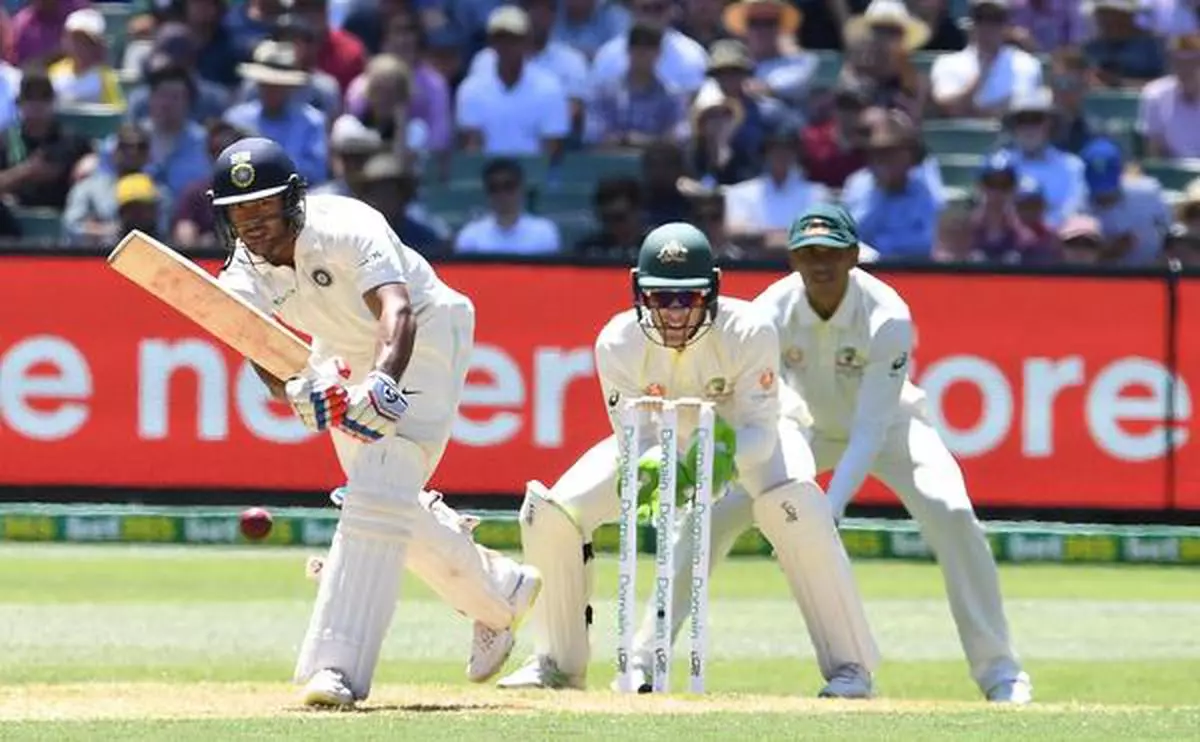 Mayank Agarwal (L) plays a shot as Australia's Tim Paine (C) and Usman Khawaja look on during day one of the third test match between Australia and India at the MCG in Melbourne, Australia.
