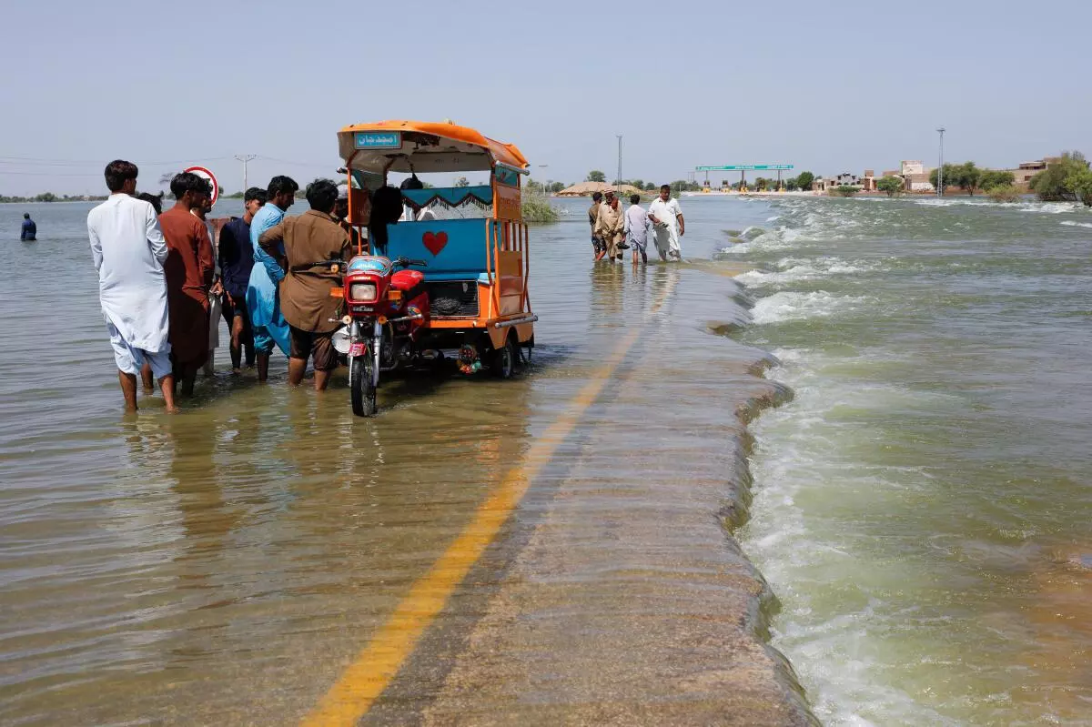 Displaced people stand on flooded highway, following rains and floods during the monsoon season in Sehwan, Pakistan, September 16, 2022. REUTERS