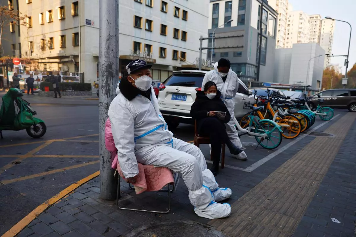 A worker in a protective suit sits near a residential compound, following the coronavirus disease outbreak in Beijing, China November 23, 2022. REUTERS