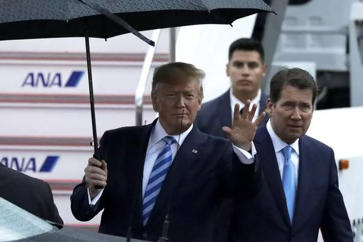 U.S. President Donald Trump waves while sheltering under an umbrella after exiting from Air Force One upon arrival at Osaka International Airport in Osaka, Japan, on Thursday, June 27, 2019. If President Trump and China’s Xi Jinping announce a new round of talks Saturday, as expected, any optimism ought to be balanced with a healthy dose of reality. Photographer: Kiyoshi Ota/Bloomberg