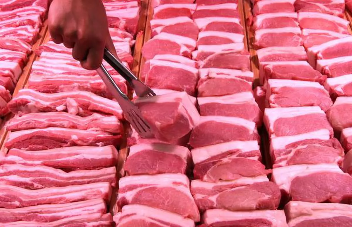 File Photo of a staff member lifting pork slice at a supermarket.
