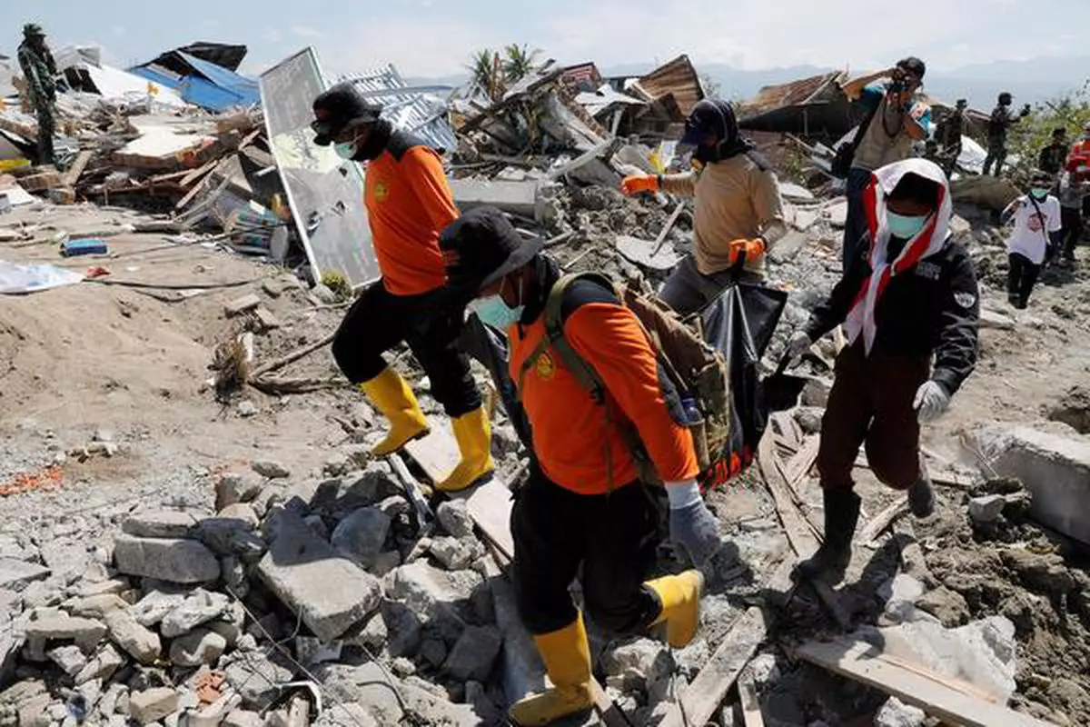 Rescue team members carry a dead body after an earthquake hit Petobo neighbourhood in Palu, Indonesia.

