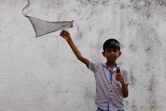 Oshada Fernando, 11, poses with his kite which his uncle made for him
