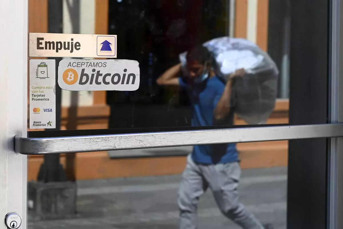 A man walks in front of a sign of a business where payments are accepted in bitcoin in San Salvador, on Thursday. President Nayib Bukele of El Salvador, the first country to make bitcoin legal tender, said Thursday the nation would buy one unit of the currency every day, doubling down in the face of public criticism of his embrace of the crypto money. 